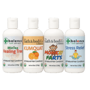 Four Balence Hair Conditioner bottles—Monkey Farts, Kumquat, Stress Relief, and Healing Tree—arranged on a rustic wood counter with fresh citrus slices and greenery, soft morning light highlighting the natural formulas.