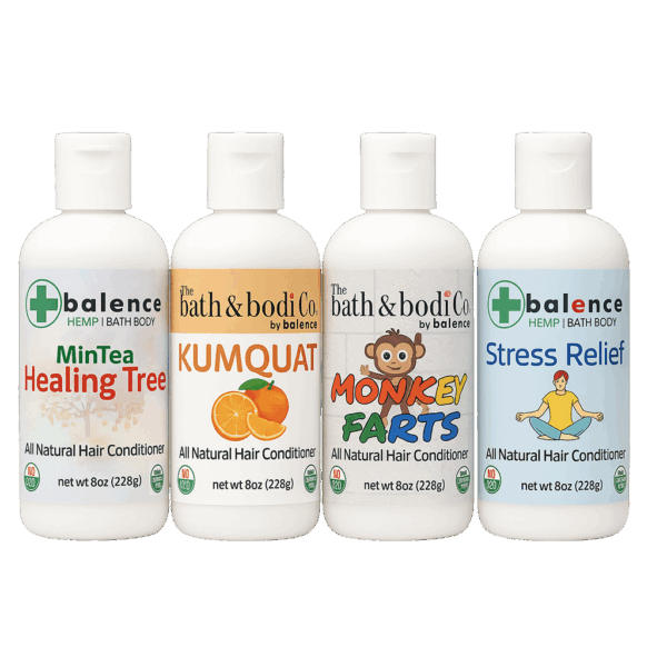Four Balence Hair Conditioner bottles—Monkey Farts, Kumquat, Stress Relief, and Healing Tree—arranged on a rustic wood counter with fresh citrus slices and greenery, soft morning light highlighting the natural formulas.
