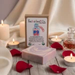Balence Love Potion #9 handmade bar soap on a rustic wooden surface with rose petals, glowing candles, and a silk cloth in warm romantic lighting.