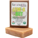 Balence Lem-O-Nut handmade soap on rustic wood with fresh lemongrass stalks, halved coconuts, and lime wedges in bright golden sunlight.