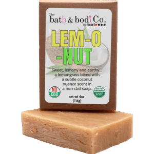 Balence Lem-O-Nut handmade soap on rustic wood with fresh lemongrass stalks, halved coconuts, and lime wedges in bright golden sunlight.