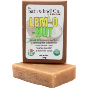 Balence Lem-O-Nut handmade soap on rustic wood with fresh lemongrass stalks, halved coconuts, and lime wedges in bright golden sunlight.