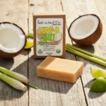 Balence Lem-O-Nut handmade soap on rustic wood with fresh lemongrass stalks, halved coconuts, and lime wedges in bright golden sunlight.