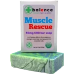 Balence Muscle Rescue hemp CBD soap on rustic wood with peppermint leaves, rosemary sprigs, eucalyptus stems, and orange slices in cool misty lighting.