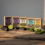 Balence Once You Go Black Activated Charcoal Soap Collection — five solid black handmade bars with labels for Unscented, Lavender, Lemongrass, Peppermint & Tea Tree, and Chamomile & Aloe, each styled with its matching natural ingredients on rustic wood in soft golden light.