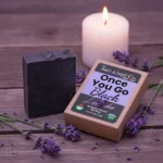 Balence Once You Go Black Lavender solid black soap bar with label, surrounded by fresh lavender sprigs and buds on rustic wood with soft purple lighting.
