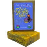 Balence Witch’s Brew handmade soap bar on an aged wooden table with candles, herbs, cinnamon sticks, and wisps of smoke creating a mystical atmosphere.