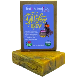 Balence Witch’s Brew handmade soap bar on an aged wooden table with candles, herbs, cinnamon sticks, and wisps of smoke creating a mystical atmosphere.