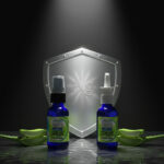 Two Balence Silver Shield sprays — a fine mist spray and vertical spray — displayed side by side on a reflective surface with aloe vera leaves and a glowing silver shield backdrop.