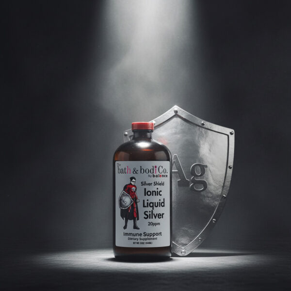 Balence Silver Shield Ionic Liquid Silver 32 oz bottle stands under a bright spotlight with a polished silver knight-style shield engraved with the chemical symbol “Ag” positioned behind it, set against a dark, misty background with subtle swirling fog and faint light rays.