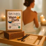 Balence Vann Oats bar soap in focus on a bamboo bath tray with vanilla beans and oat flakes, glowing candles nearby. In soft bokeh behind, a woman wrapped in a white towel sits at the edge of a sunlit bathtub, gently resting her hands on her shoulders in a serene early-morning spa setting.