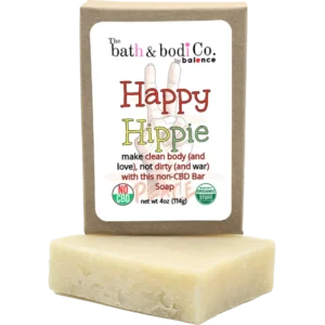 Balence Happy Hippie handmade soap bar on rustic wood with tie-dye cloth, hemp leaves, geranium flowers, patchouli sprigs, and incense smoke in warm sunlight.